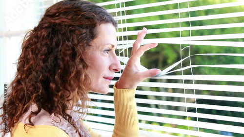 Woman peering through roller blind photo