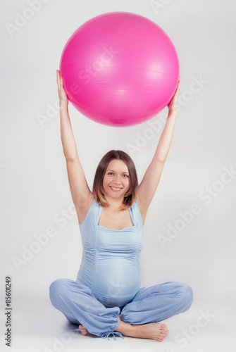 Pretty pregnant woman doing exercise with big gymnastic ball