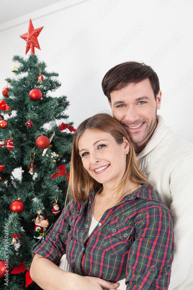 Couple smiling beside the chrismas tree Couple smiling beside the chrismas tree