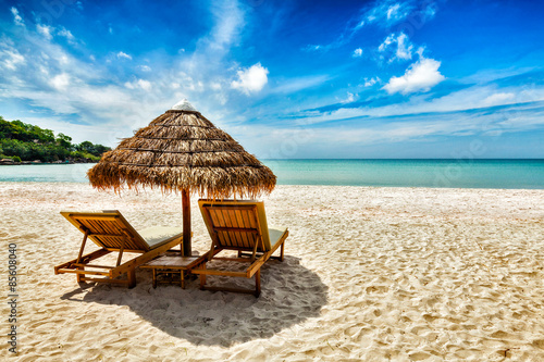 Two lounge chairs under tent on beach