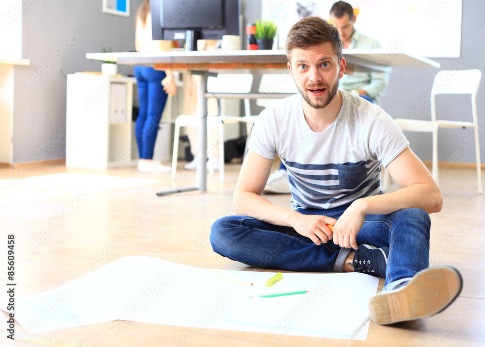 Handsome designer sit in his office with colleagues discussing Handsome designer sit in his office with colleagues discussing