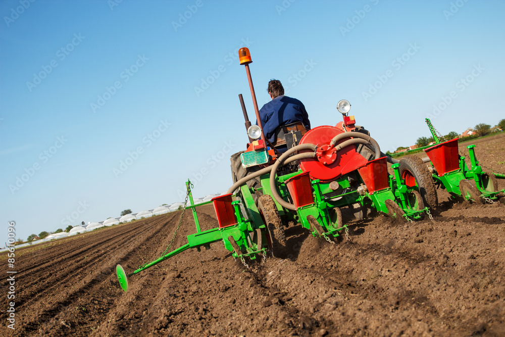 Obraz premium Farmer in Old fashioned tractor sowing crops at field