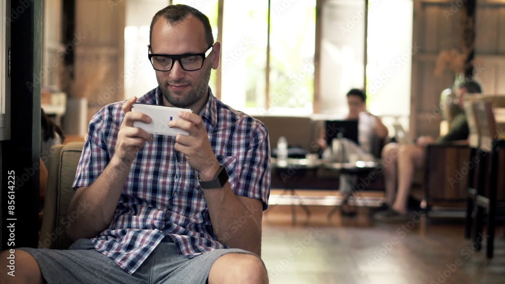Young man playing game on smartphone sitting in cafe
Young man playing game on smartphone sitting in cafe