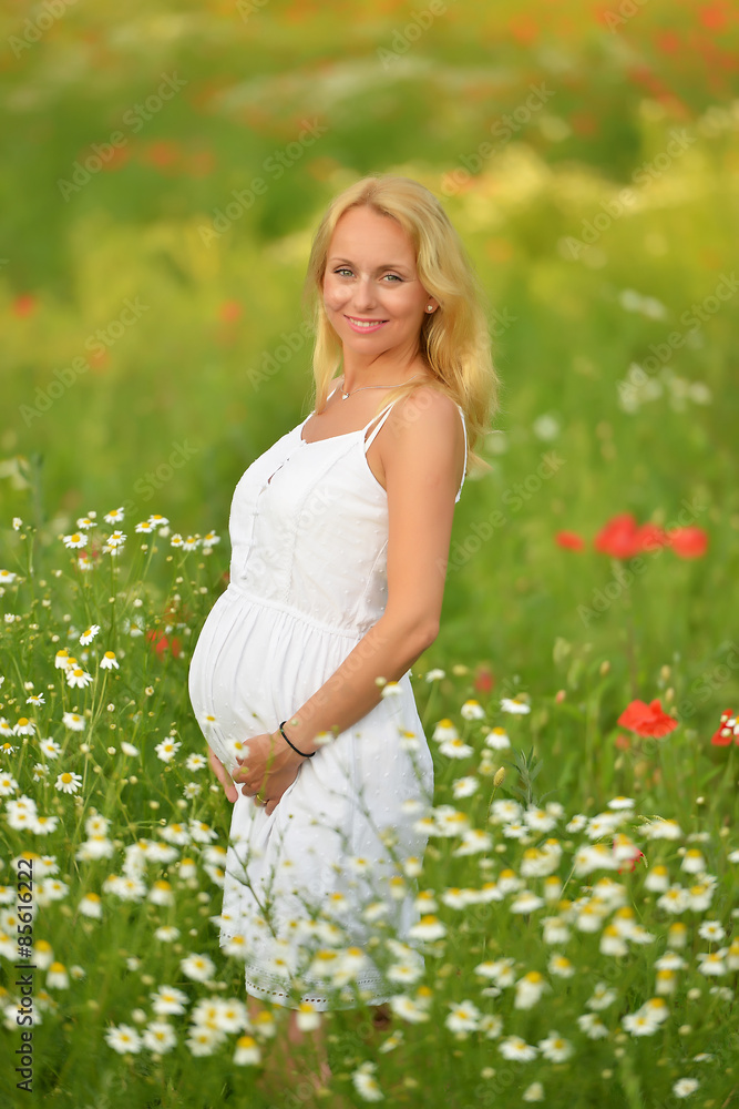 Pregnant happy woman in a flowering poppy field outdoors Pregnant happy woman in a flowering poppy field outdoors