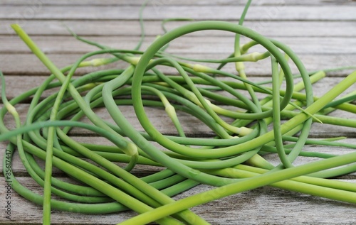 Bunches of freshly picked garlic scape on a wooden table