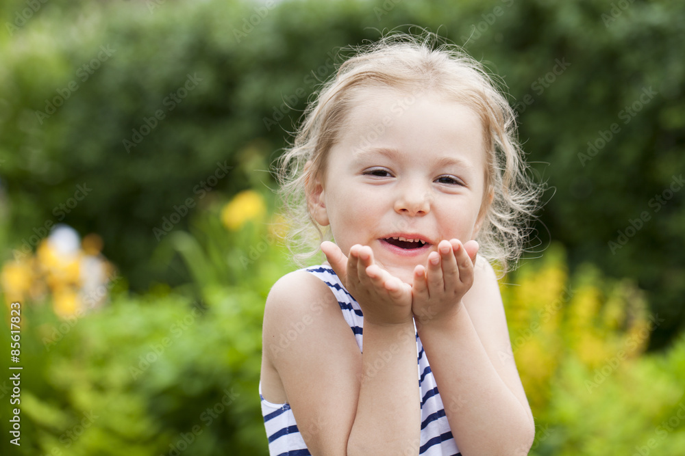 Blonde little Girl Blowing a Kiss, on summer park background Blonde little Girl Blowing a Kiss, on summer park background