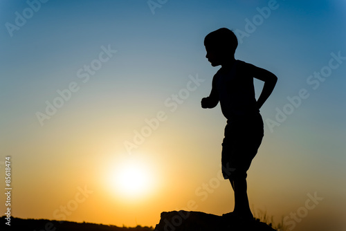 Little boy silhouetted against the sunset