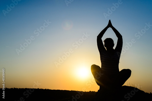 Fototapeta Naklejka Na Ścianę i Meble -  Woman meditating in front of the rising sun
