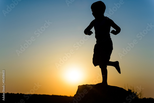 Young boy silhouetted by the sunset