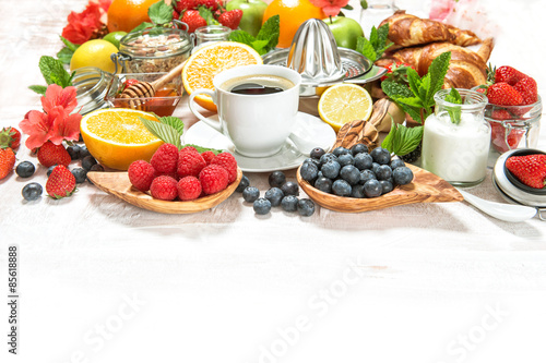 Healthy breakfast table with coffee, croissants, muesli, fresh b