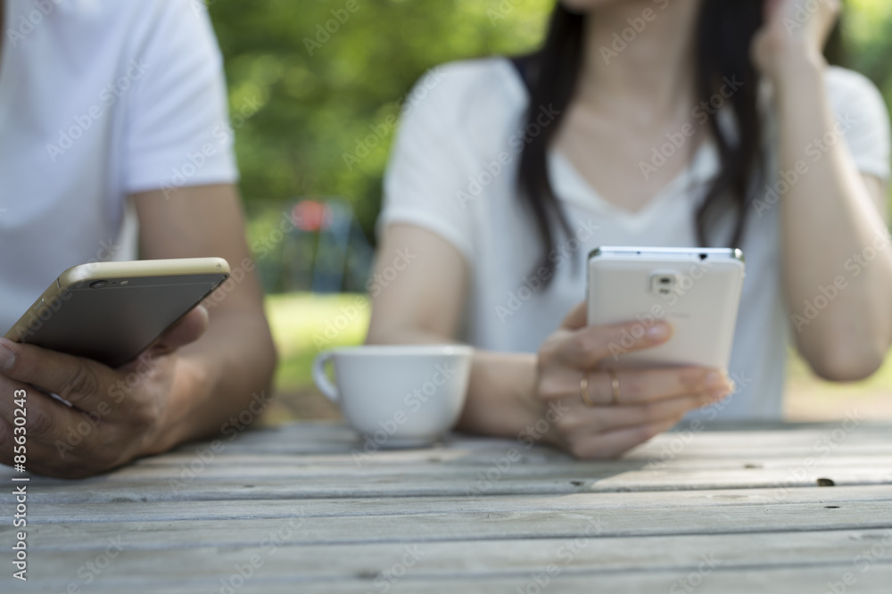 The couple are looking at a smartphone in the garden The couple are looking at a smartphone in the garden