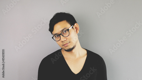 A man with eyeglasses is looking at camera with easy pose.