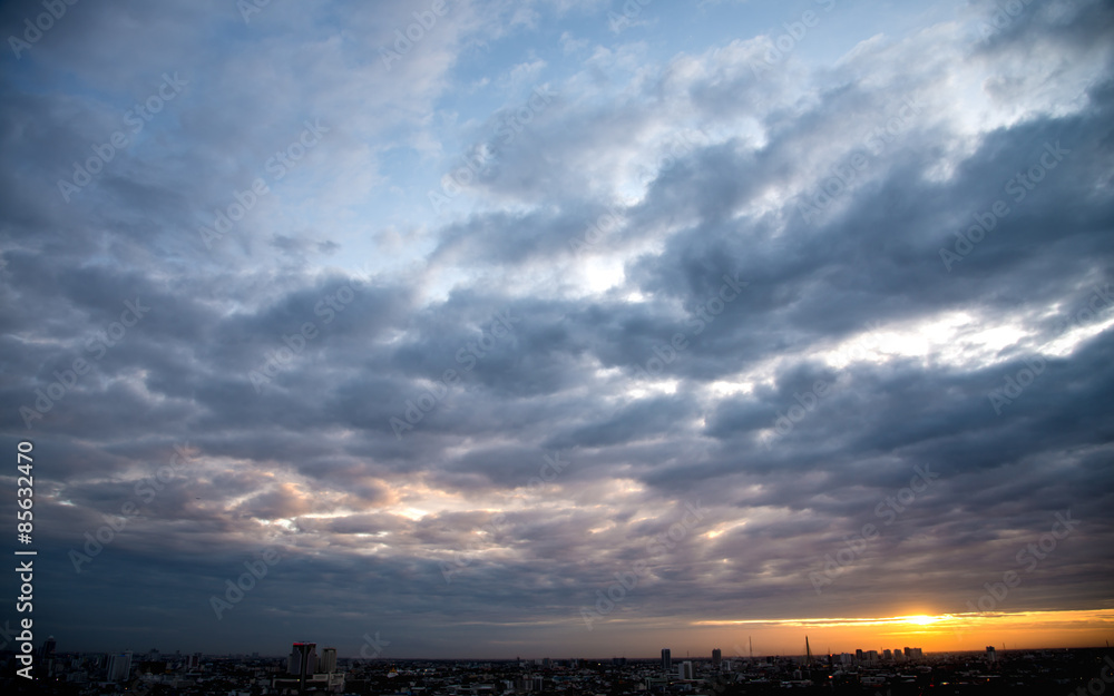 Sunset with cloudy sky above city
