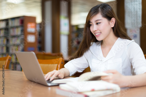 Asian beautiful female student study in library with laptop