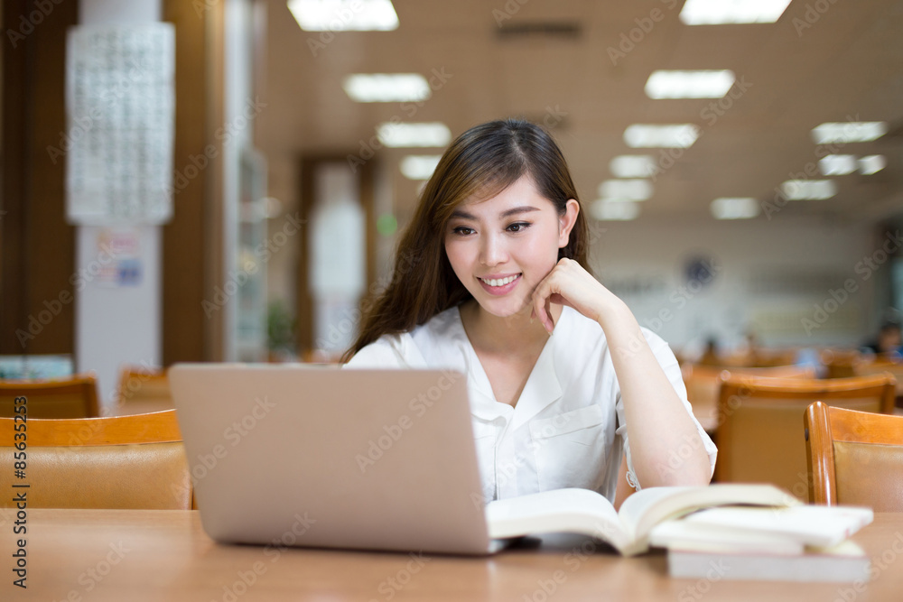 Asian beautiful female student study in library with laptop Asian beautiful female student study in library with laptop