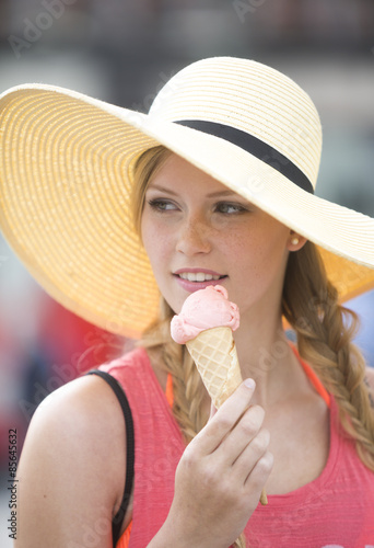 Beautiful girl with straw hat eating ice cream