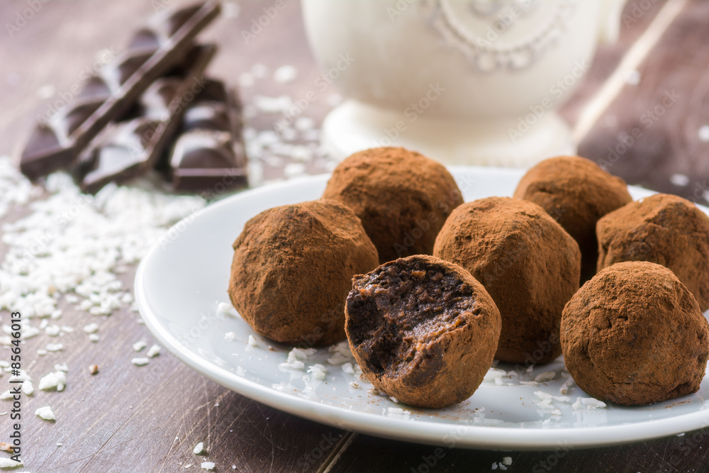 Homemade healthy vegan chocolate truffles with dates, coconut flakes and rolled oats served on white plate Homemade healthy vegan chocolate truffles with dates, coconut flakes and rolled oats served on white plate