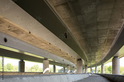 Graceful ballerina doing dance exercises on a concrete bridge 