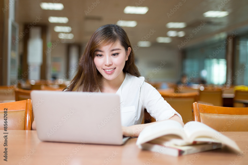 Asian beautiful female student study in library with laptop Asian beautiful female student study in library with laptop