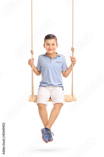 Joyful little boy sitting on a swing