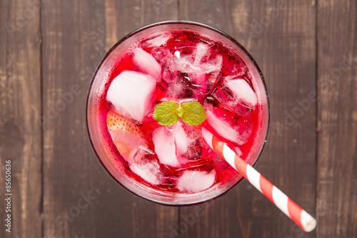 Red Cocktail with mint and ice on wooden table