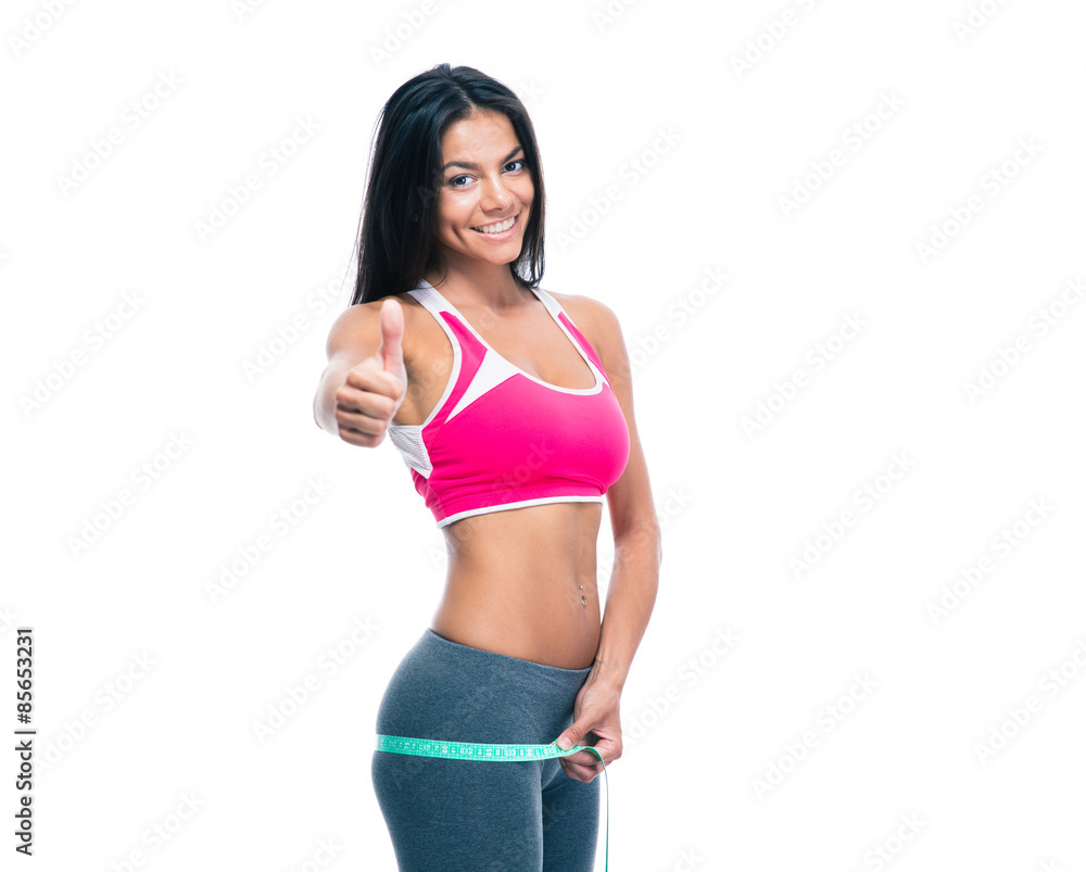 Fitness woman measure her buttocks with a measuring tape and showing thumb up isolated on a white background. Looking at camera