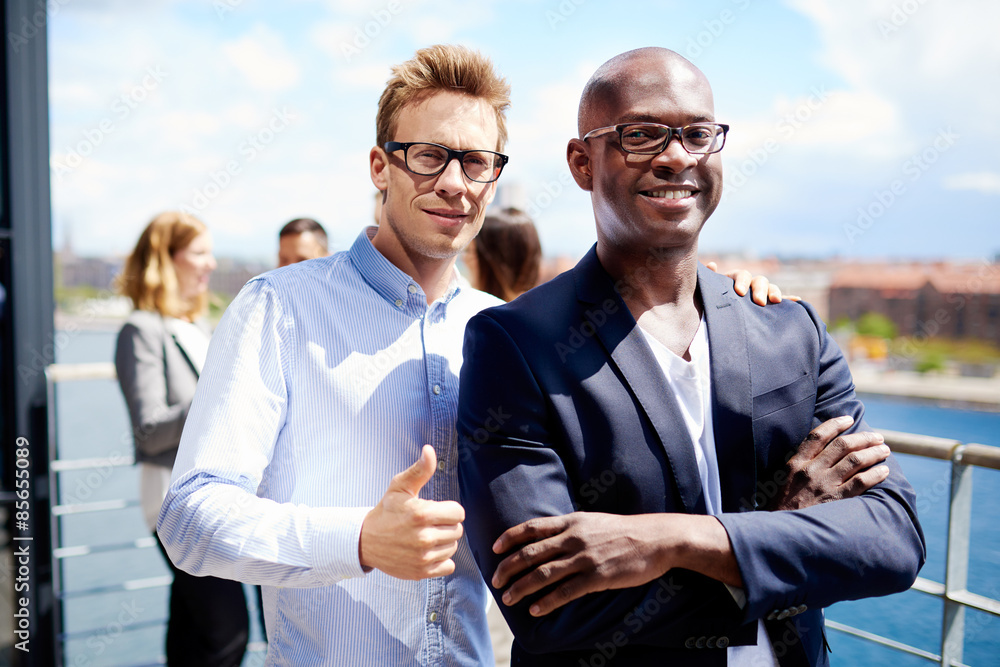 Two colleagues standing together smiling Two colleagues standing together smiling