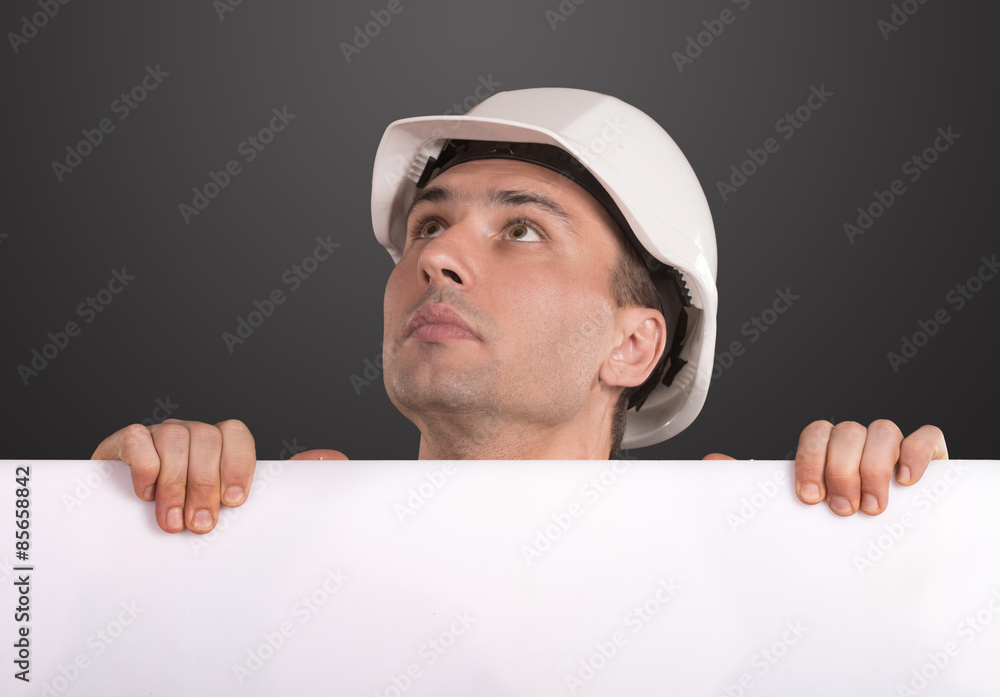 Workman in white hardhat holding a blank copy space and looking up Workman in white hardhat holding a blank copy space and looking up