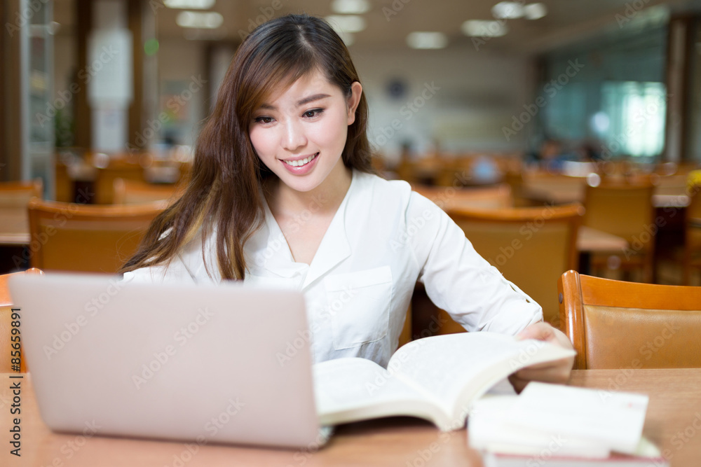 Asian beautiful female student study in library with laptop Asian beautiful female student study in library with laptop