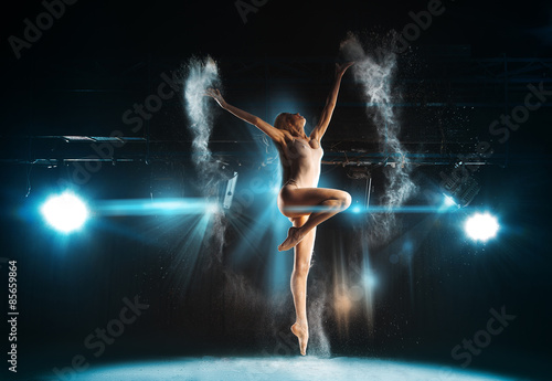 Wonderful adult ballerina posing on stage against spotlights © ponomarencko