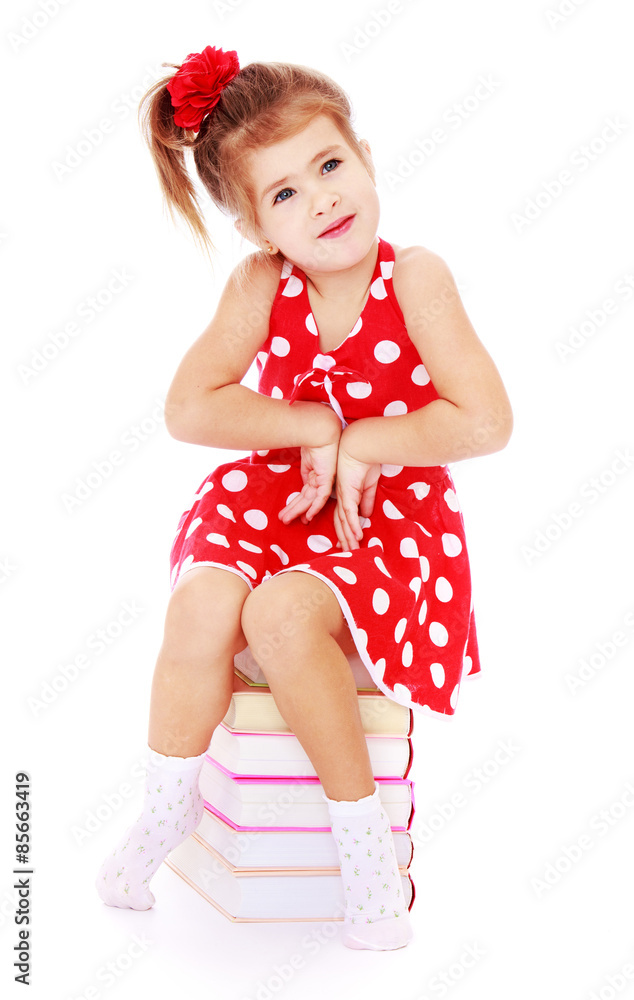 Beautiful little girl sitting on stack of books Stock Photo | Adobe Stock