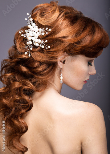 Portrait of a beautiful ginger woman in the image of the bride. Picture taken in the studio on a grey background