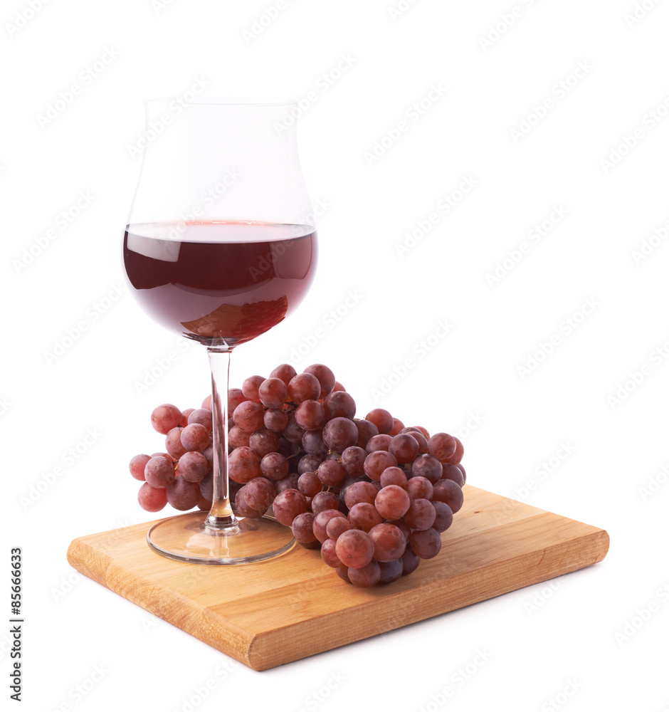 Glass of red wine next to a branch of grapes