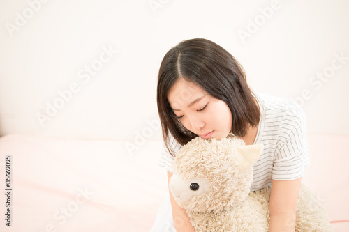 ベッドの上で悩む女性