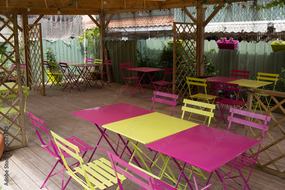 View of an empty outdoor cafe in yellow and pink