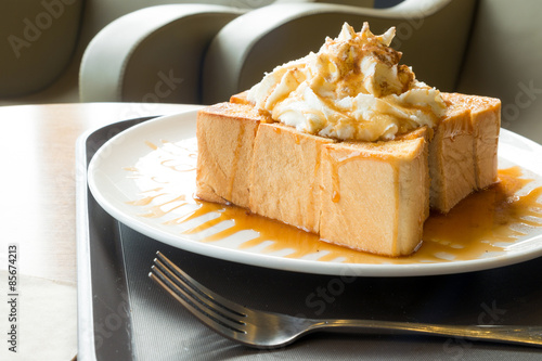 Golden honey toast in the white dish with whipped cream on top