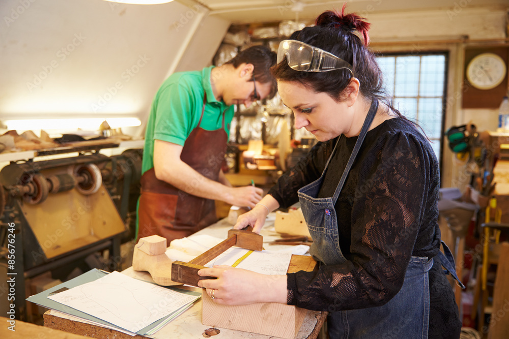 Two young shoemakers preparing shoe lasts in a workshop Two young shoemakers preparing shoe lasts in a workshop