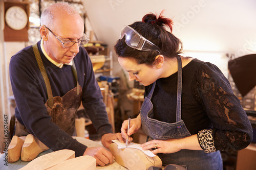 Photos Senior shoemaker training apprentice to make shoe lasts