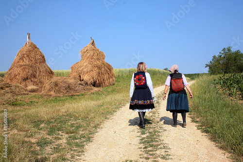 Summer mountain village outskirts with haystacks, stack of hay, two womans photo