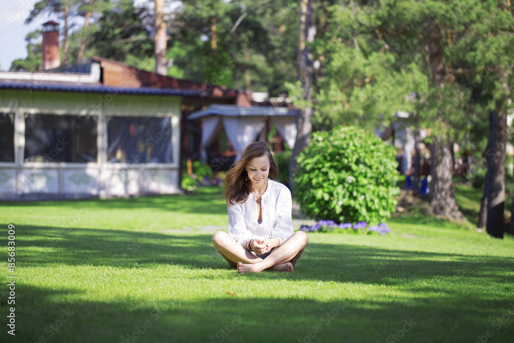 Smiling girl on the lawn in the Lotus position