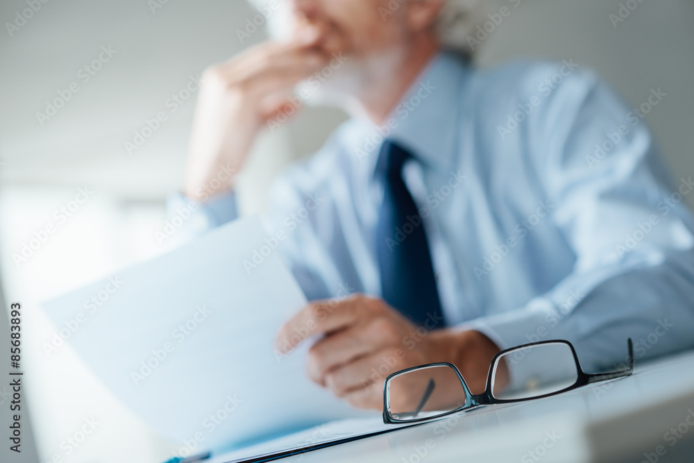 Pensive businessman reading a contract Pensive businessman reading a contract