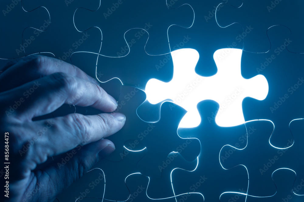 Hand insert jigsaw, conceptual image of business strategy Hand insert jigsaw, conceptual image of business strategy