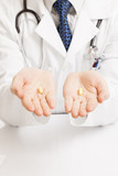 Doctor holding one pill on each palm - studio shot