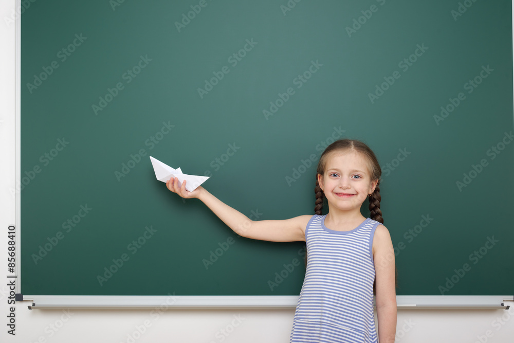 Schoolgirl with paper ship near school board Schoolgirl with paper ship near school board
