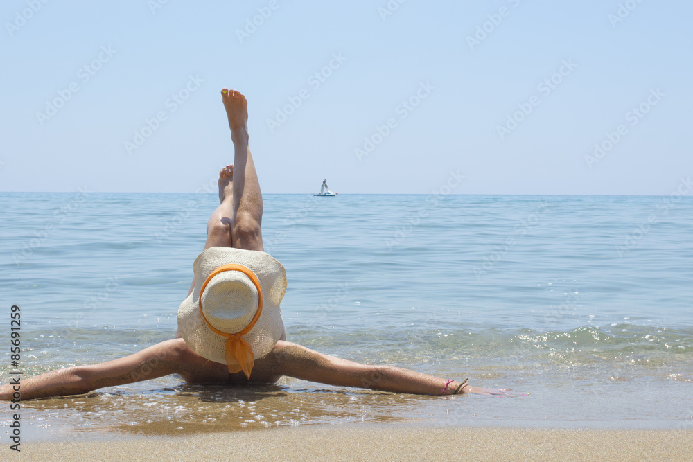 Fototapeta premium Girl lying on the beach with legs lifted up
