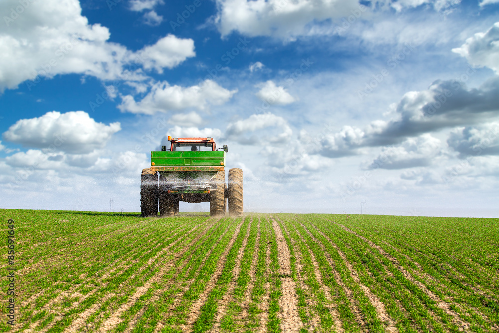 Farmer in tractor fertilizing wheat field at spring with npk Farmer in tractor fertilizing wheat field at spring with npk