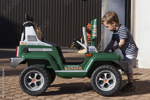Little boy repairing a toy car under the hood