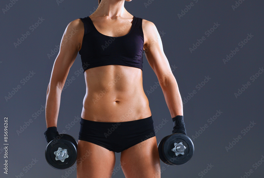 Athletic woman pumping up muscules with dumbbells Athletic woman pumping up muscules with dumbbells
