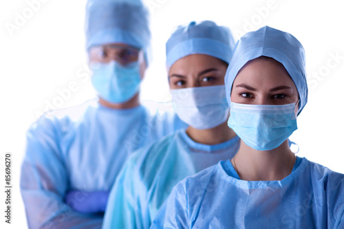Surgeons team  wearing protective uniforms caps and masks 