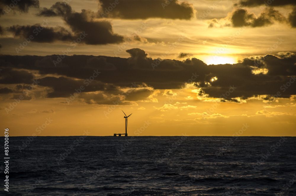 Windrad im Meer am Horizont mit Sonnenuntergang